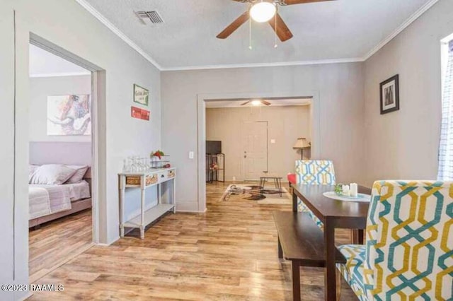 dining area featuring visible vents, a ceiling fan, light wood-style flooring, and ornamental molding