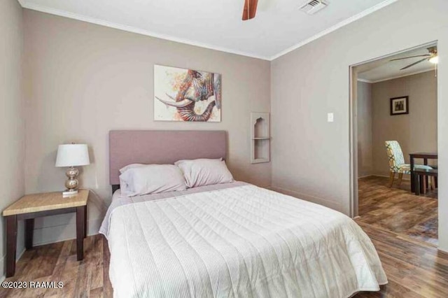 bedroom with crown molding, ceiling fan, visible vents, and wood finished floors