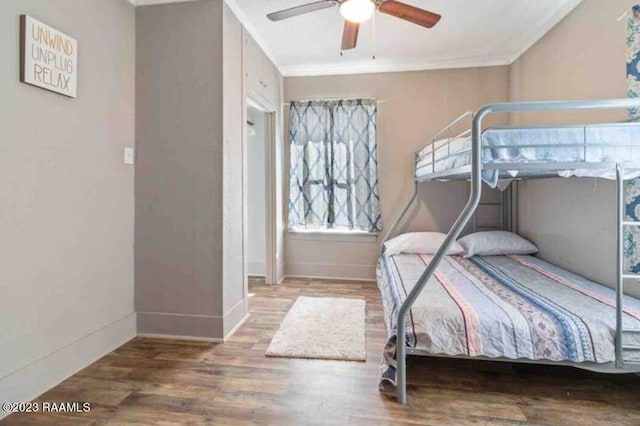 bedroom featuring baseboards, ornamental molding, a ceiling fan, and wood finished floors