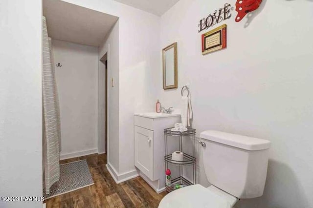 bathroom featuring vanity, baseboards, toilet, and wood finished floors