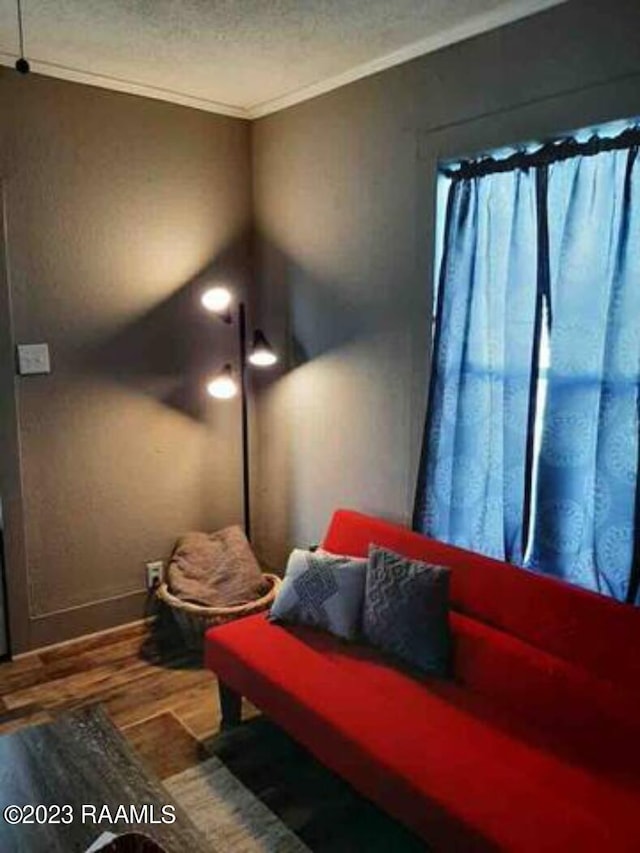 interior space featuring crown molding, a textured ceiling, baseboards, and wood finished floors