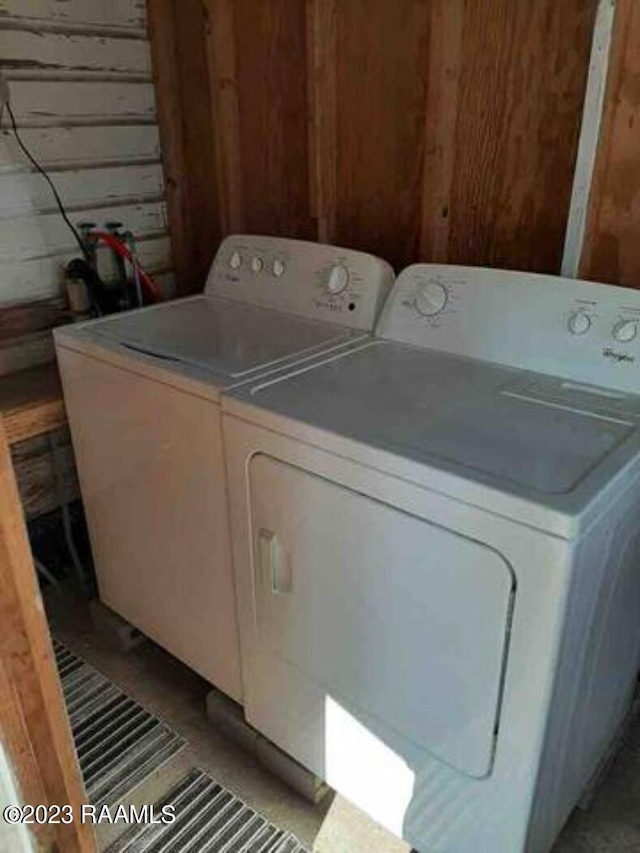 laundry room with laundry area, wood walls, and washing machine and clothes dryer