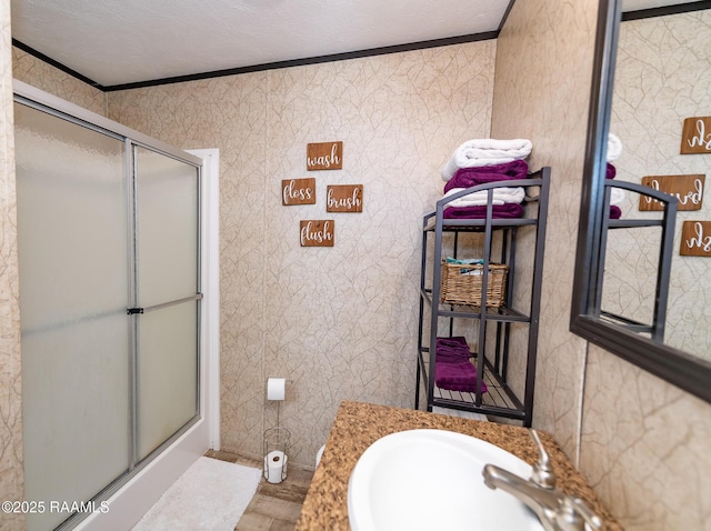 bathroom with a stall shower, crown molding, and a sink
