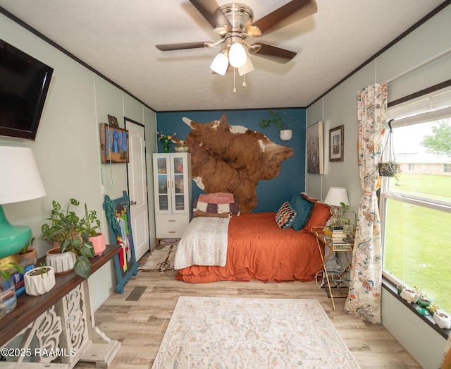 bedroom with ornamental molding, wood finished floors, and ceiling fan