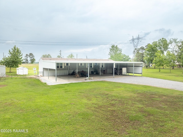 view of front of property with fence, a carport, a front lawn, and an outbuilding