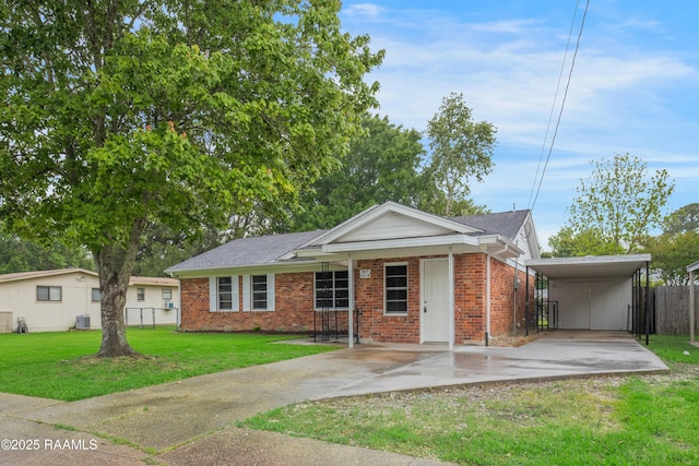 ranch-style house featuring a front lawn, fence, brick siding, concrete driveway, and a carport