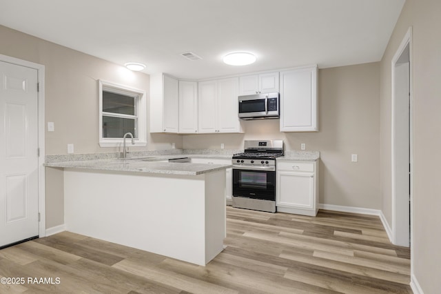 kitchen with white cabinets, stainless steel appliances, a peninsula, and visible vents