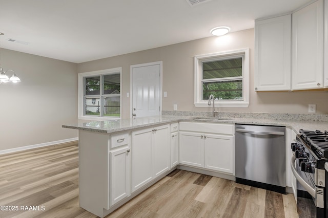 kitchen with appliances with stainless steel finishes, a sink, a peninsula, light wood finished floors, and a wealth of natural light