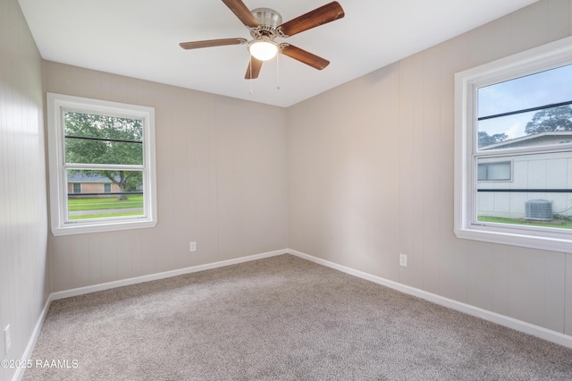 carpeted spare room featuring plenty of natural light, a ceiling fan, and baseboards