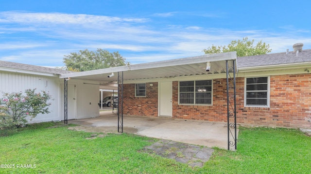 back of house featuring a yard, brick siding, and an attached carport