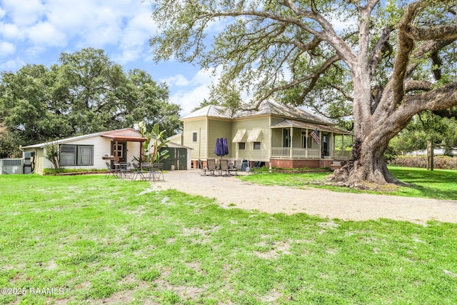 rear view of property featuring a patio, dirt driveway, a lawn, and a sunroom