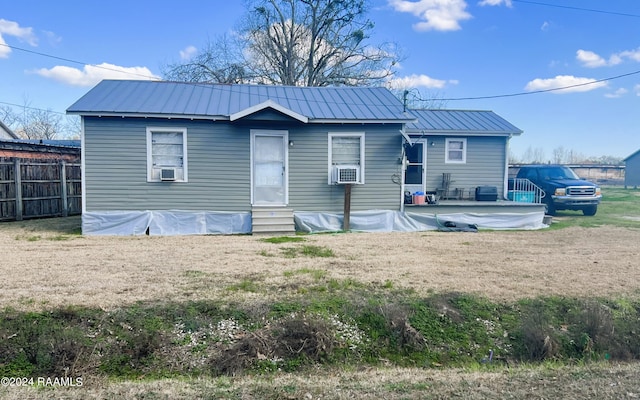 rear view of property with entry steps, fence, cooling unit, and metal roof