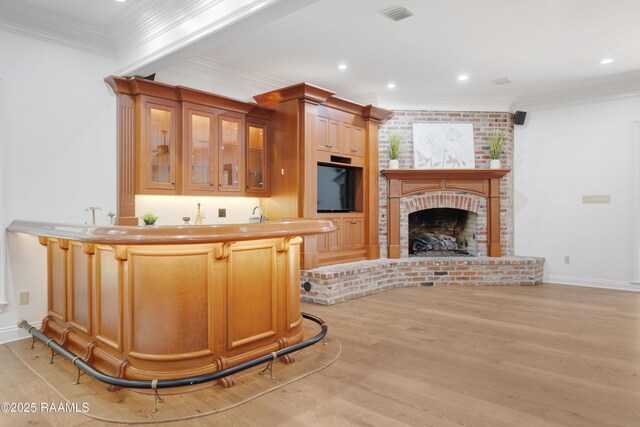 110 Interlaken Dr, New Iberia, LA 70563 - kitchen featuring light wood-type flooring, a fireplace, a kitchen bar, glass insert cabinets, and crown molding