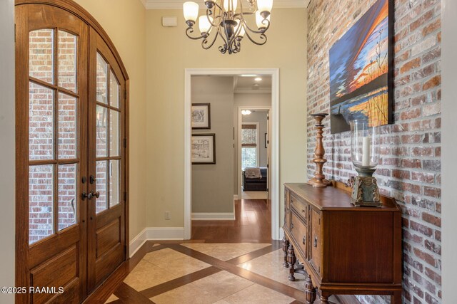 foyer featuring crown molding, baseboards, an inviting chandelier, and french doors