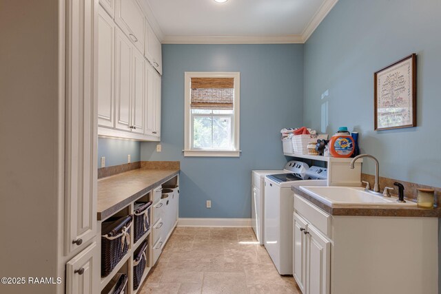 washroom with crown molding, washing machine and dryer, baseboards, a sink, and cabinet space
