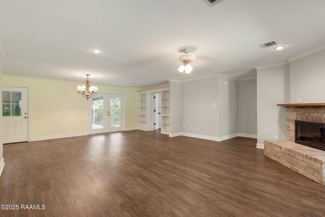 unfurnished living room featuring a fireplace, a chandelier, dark wood finished floors, baseboards, and visible vents