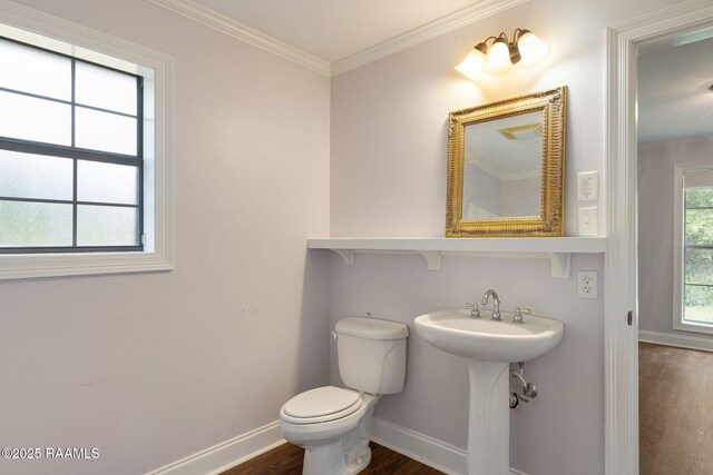 bathroom featuring baseboards, ornamental molding, wood finished floors, and toilet