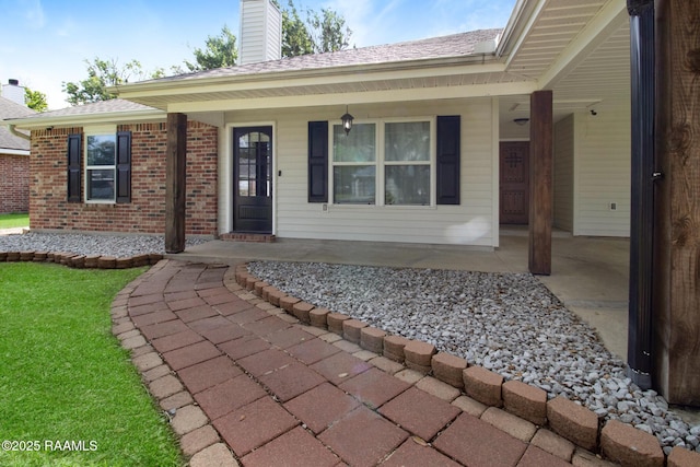 view of front of home featuring brick siding, covered porch, and a chimney