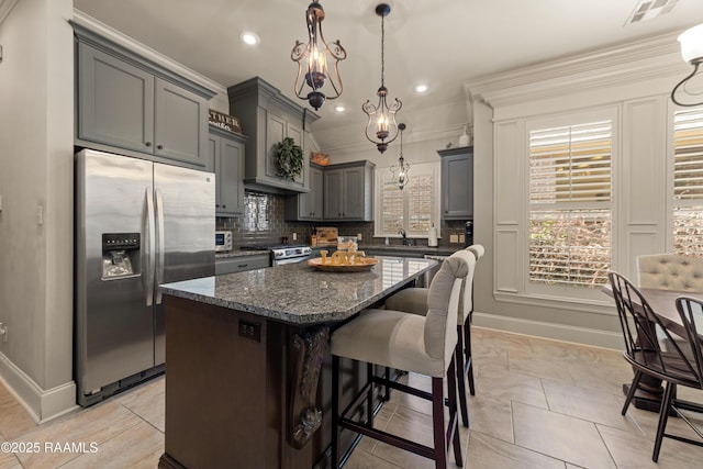 kitchen featuring appliances with stainless steel finishes, baseboards, a center island, and visible vents
