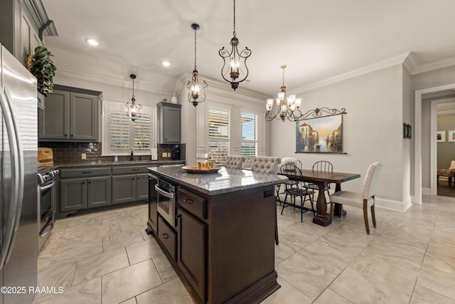 kitchen with crown molding, an inviting chandelier, a kitchen island, dark stone countertops, and backsplash