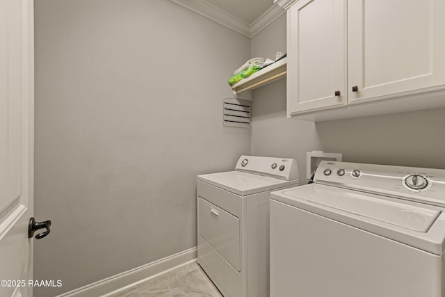 clothes washing area featuring crown molding, marble finish floor, baseboards, washing machine and clothes dryer, and cabinet space