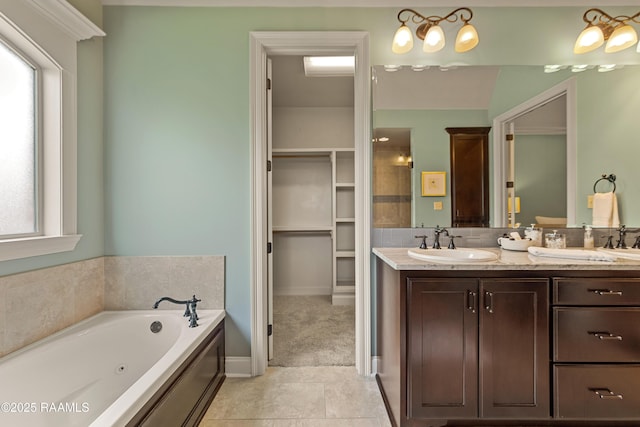 bathroom with a walk in closet, a sink, tile patterned flooring, double vanity, and a jetted tub
