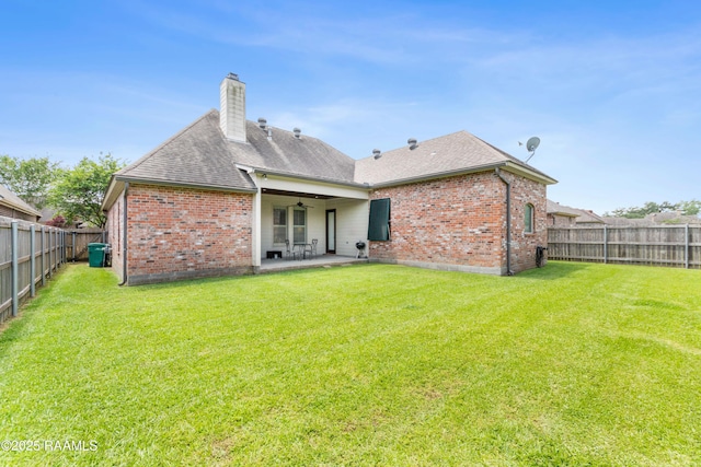 rear view of property with a fenced backyard, a chimney, a patio area, and brick siding