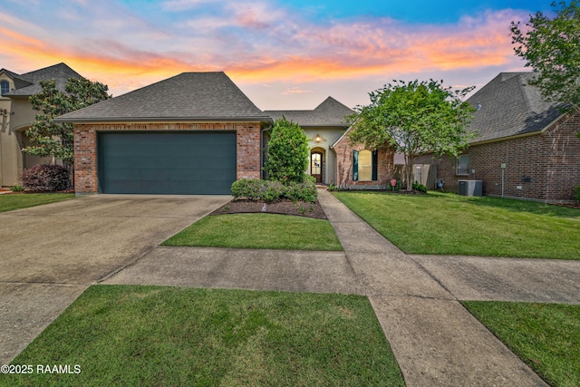 view of front of house featuring driveway, central AC unit, a garage, brick siding, and a front lawn