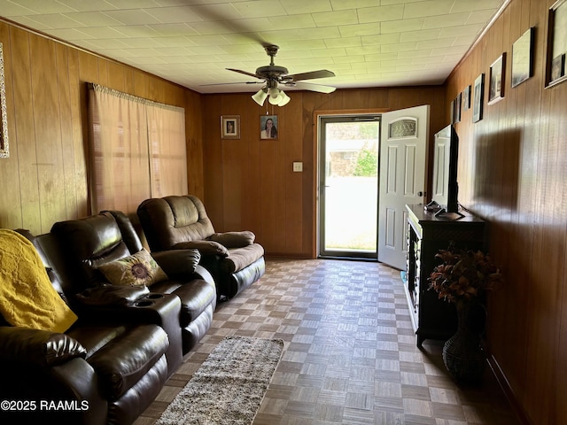 living room with a ceiling fan and wood walls