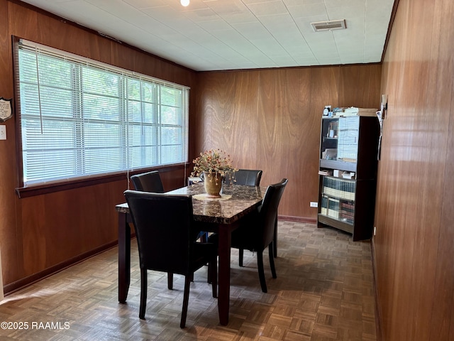 dining area with visible vents, wood walls, and baseboards