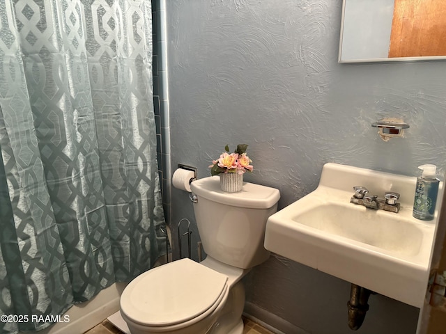bathroom featuring a sink, a shower with curtain, and toilet