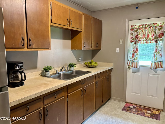kitchen with a sink, freestanding refrigerator, and light countertops