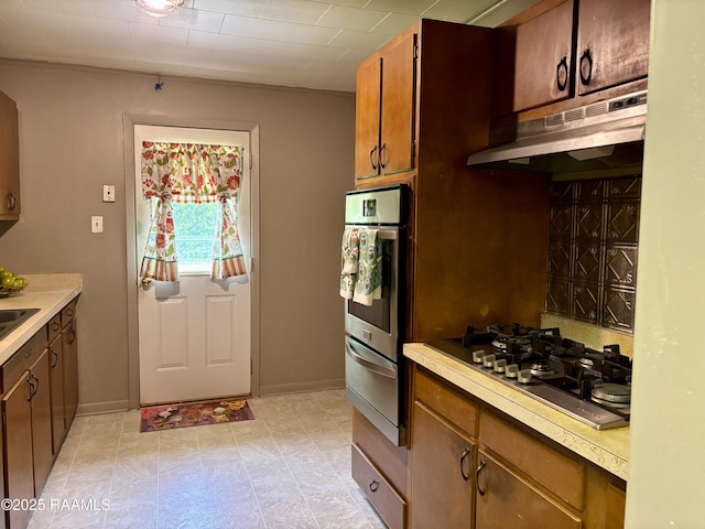 kitchen with light countertops, a warming drawer, under cabinet range hood, and stainless steel appliances