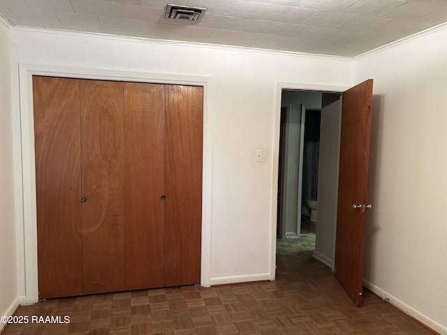 unfurnished bedroom featuring visible vents, baseboards, crown molding, and a closet