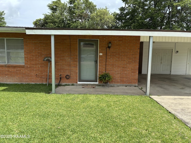entrance to property featuring a lawn, brick siding, driveway, and an attached carport