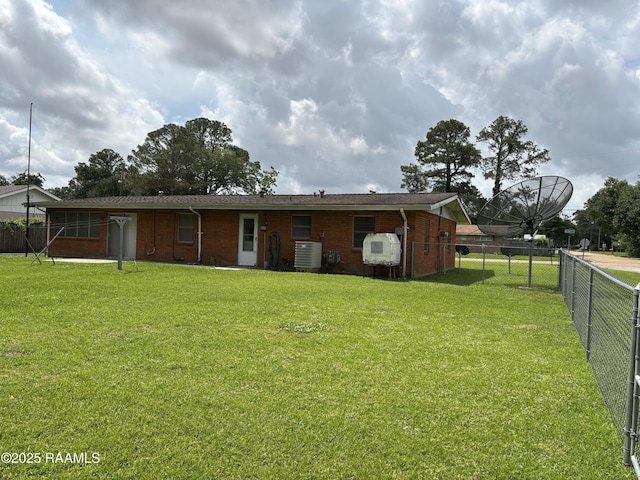 back of house with a lawn, fence, brick siding, and cooling unit