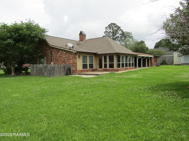 back of house with a sunroom, a lawn, fence, and brick siding