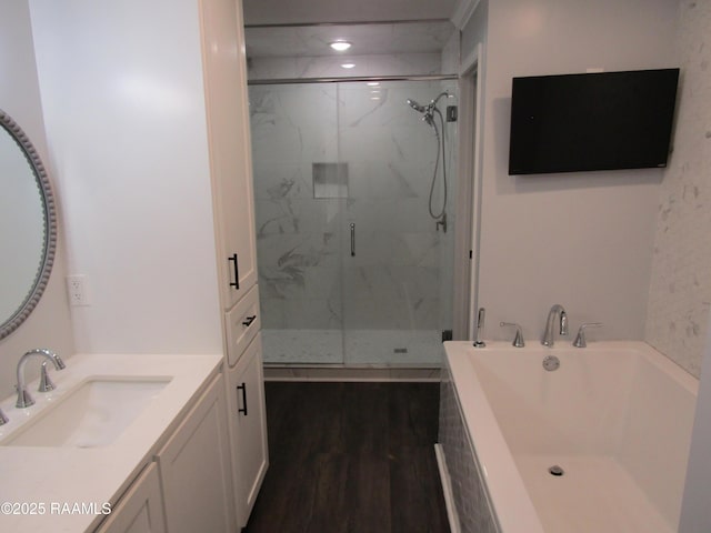 bathroom featuring wood finished floors, a marble finish shower, a garden tub, and vanity
