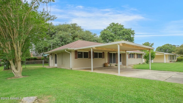 rear view of house with fence, brick siding, a lawn, driveway, and a carport