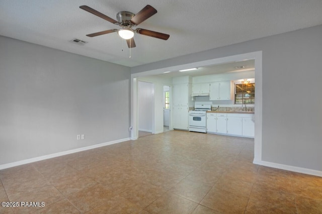 unfurnished living room featuring visible vents, a sink, baseboards, and ceiling fan