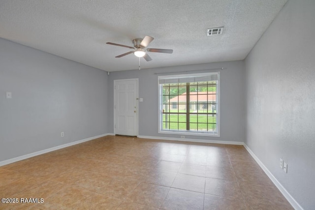 spare room with visible vents, a ceiling fan, a textured ceiling, and baseboards