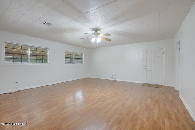 spare room with a ceiling fan, baseboards, visible vents, and light wood-type flooring