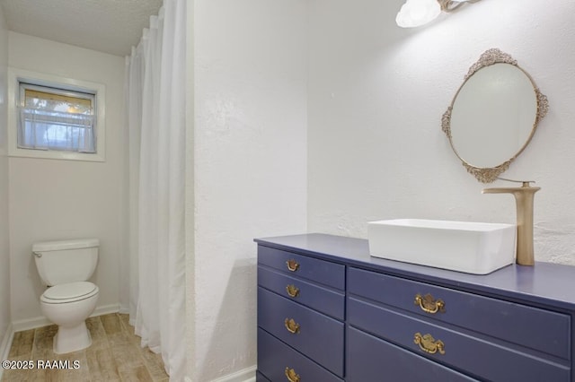 full bathroom with vanity, baseboards, toilet, and wood finished floors