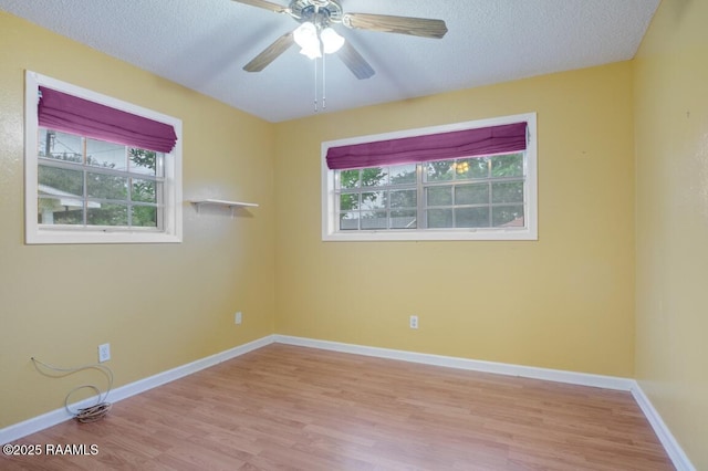 unfurnished room featuring plenty of natural light, baseboards, ceiling fan, and wood finished floors