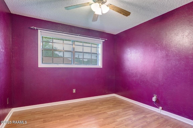 empty room with a ceiling fan, a textured ceiling, wood finished floors, and a wealth of natural light