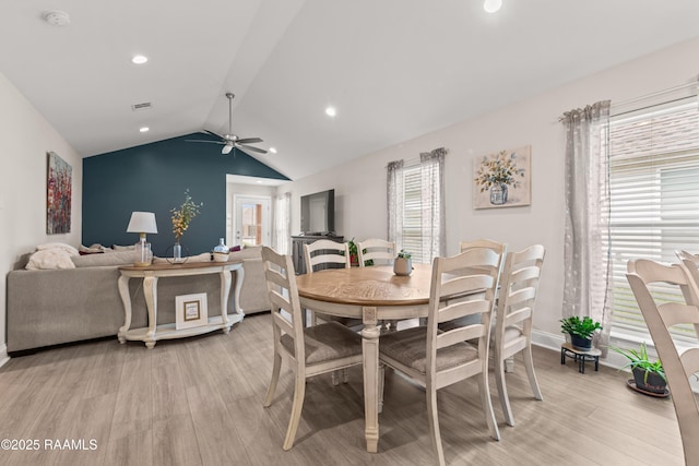 dining space with light wood-type flooring, ceiling fan, vaulted ceiling, and a healthy amount of sunlight