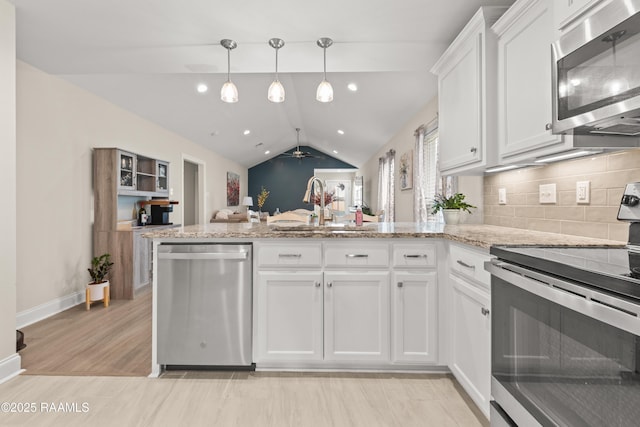 kitchen with a peninsula, lofted ceiling, white cabinetry, a sink, and stainless steel appliances
