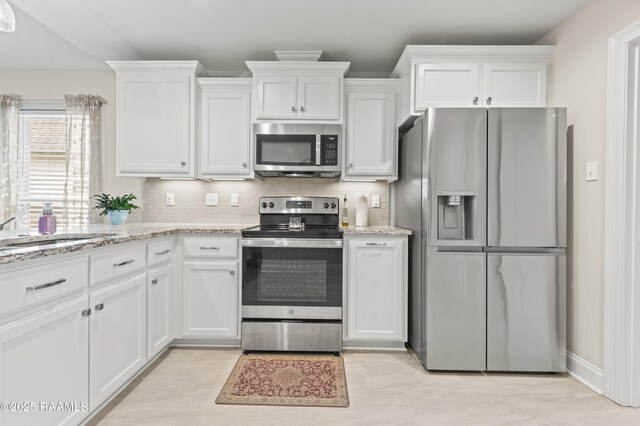 kitchen featuring tasteful backsplash, white cabinets, light stone countertops, and stainless steel appliances