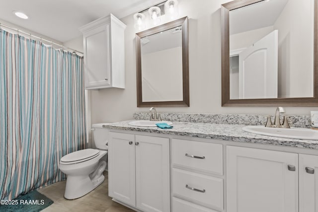 bathroom with a shower with shower curtain, double vanity, toilet, and a sink