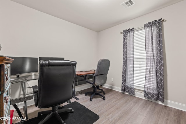 office space with baseboards, a wealth of natural light, wood finished floors, and visible vents
